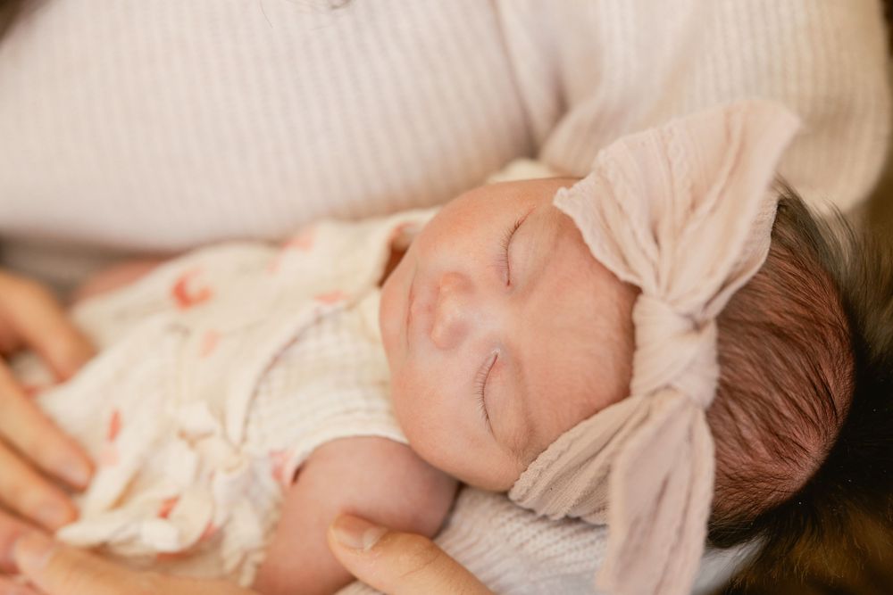 Sleeping baby in soft natural lighting wearing white clothing.