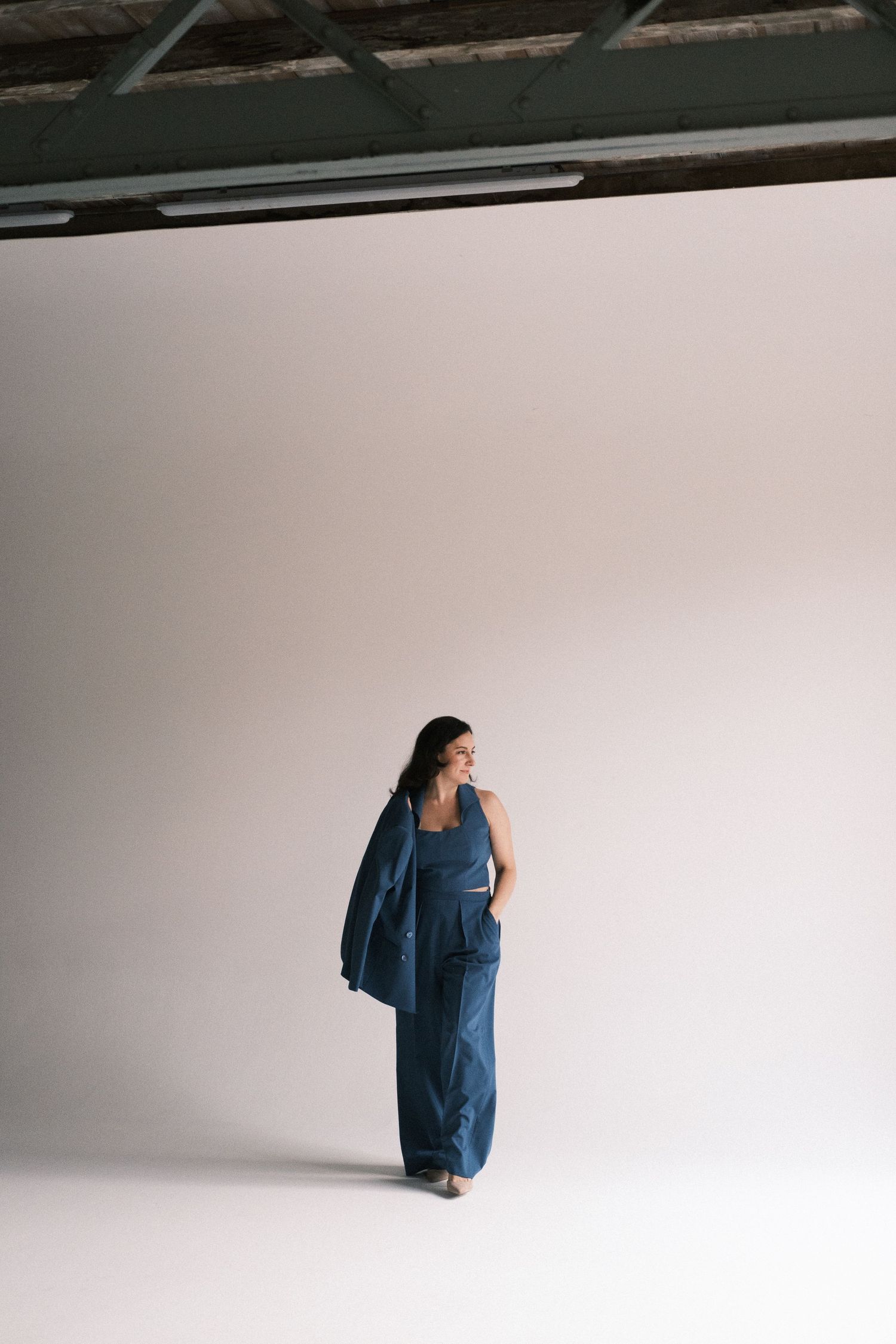 A figure in a flowing blue dress moves through a minimalist white space in a progressive sequence of poses.