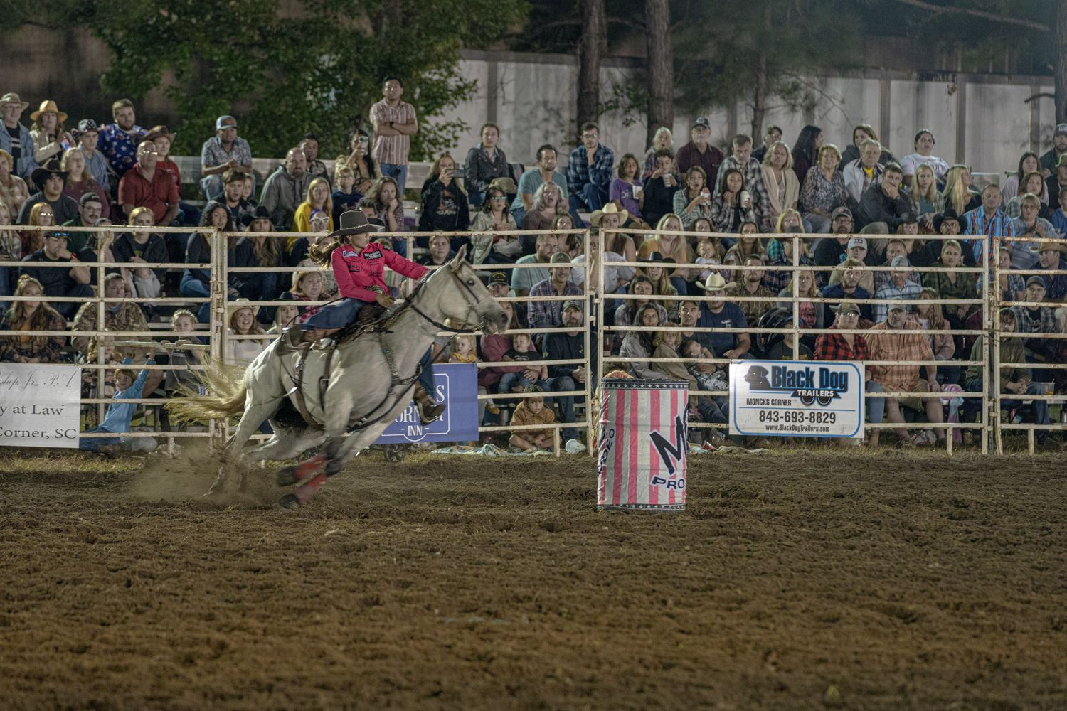 Panoramic view of a crowded rodeo arena during an evening event.