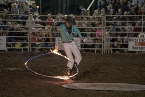 Dramatic moment at a rodeo as a horse bucks wildly in the arena while spectators watch from the stands.