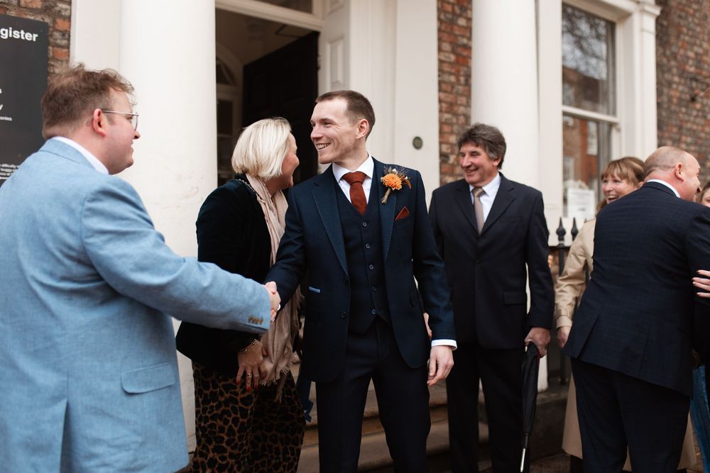 Guests mingle and socialize at an elegant reception in front of a brick wall backdrop.