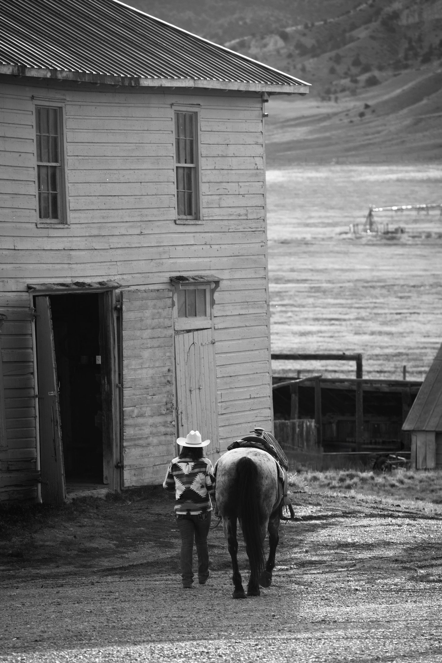 Black and white sequence of photos showing a person walking with a horse near a rural building in a mountainous landscape.