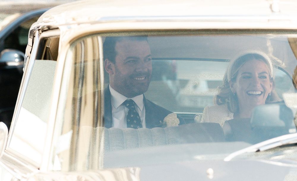A group of people laugh joyfully while riding in a vintage car with beige interior. Paris vintage style photography.