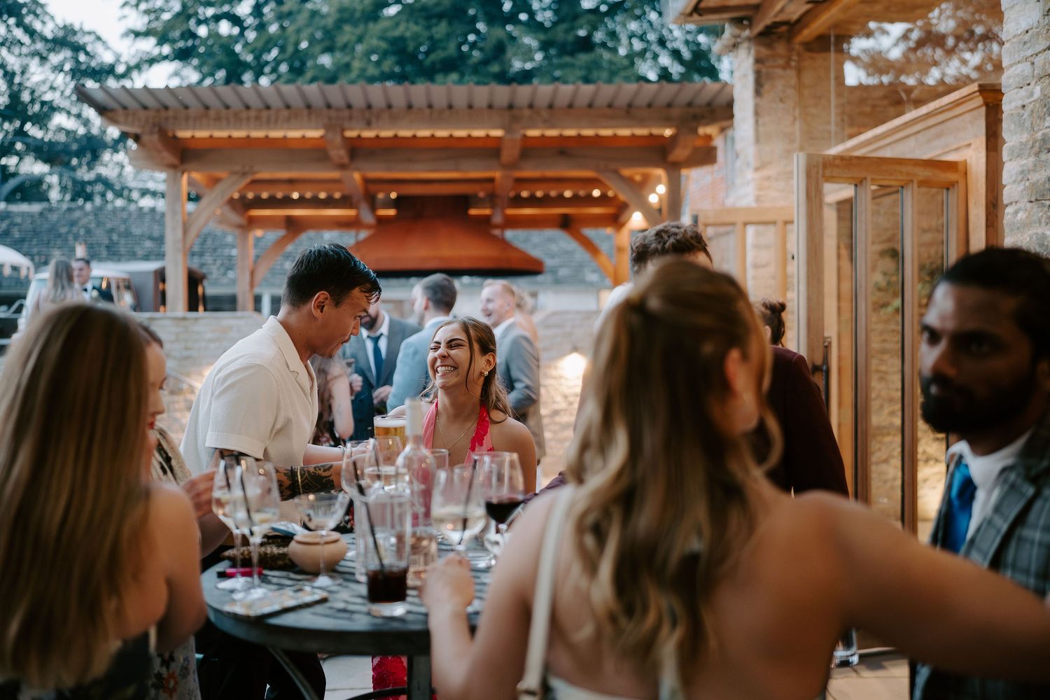 wedding guests laughing during cocktail hour at ivy lodge wedding in cirencester
