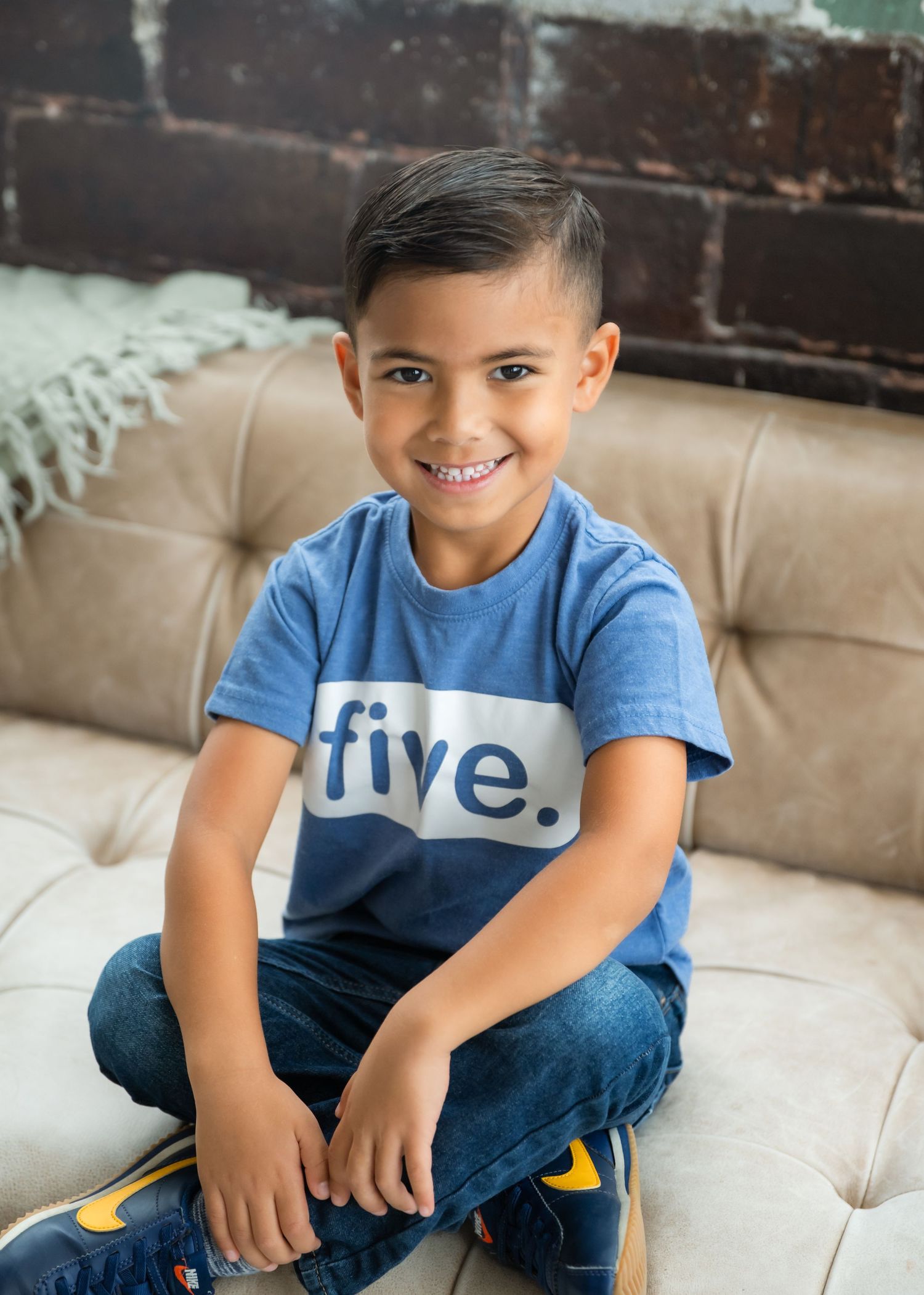 A child in a plaid shirt leans excitedly over a large blue exercise ball against a white background with yellow accent.