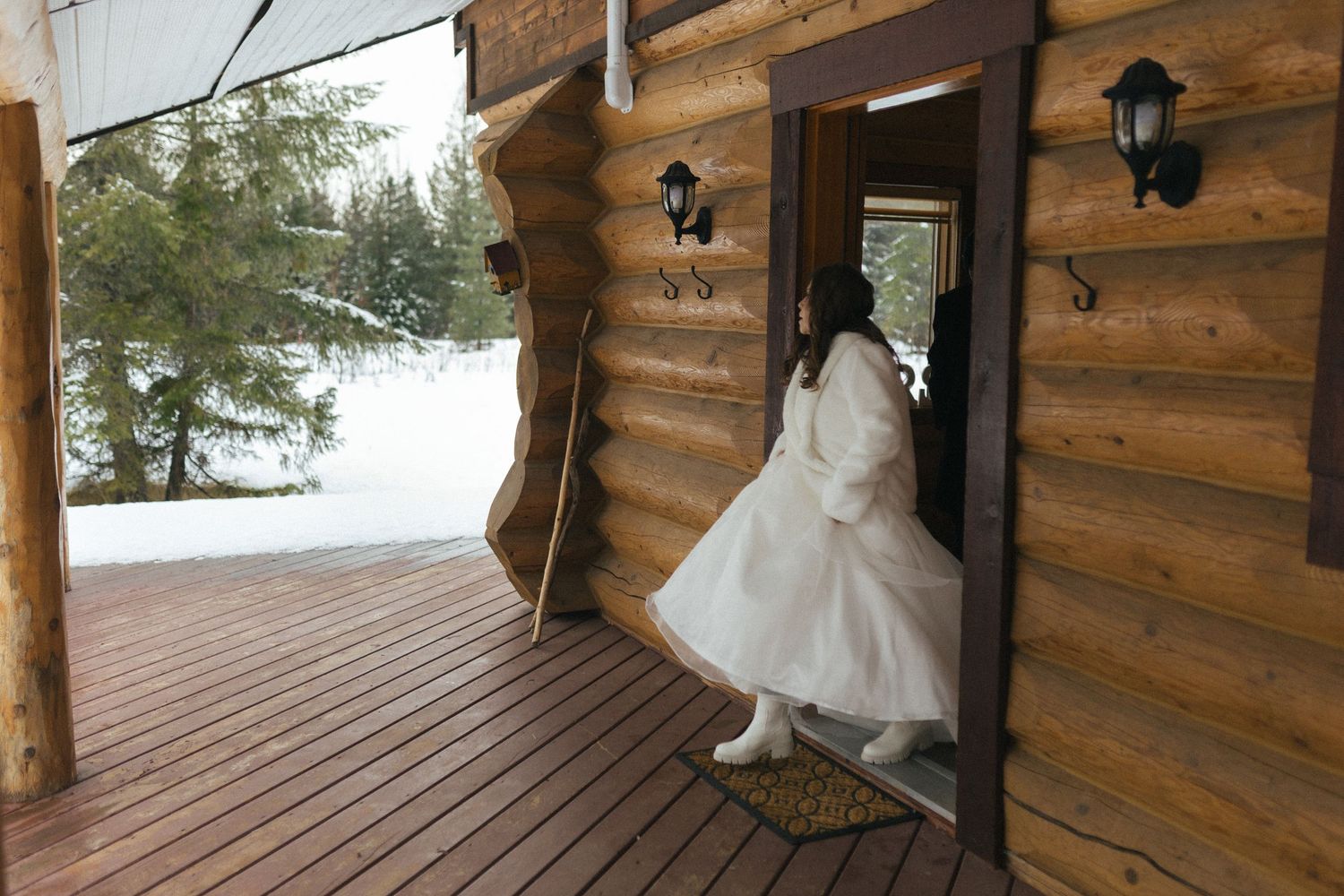 bride walks out of cedar cabin onto snowy porch during Revelstoke Elopement