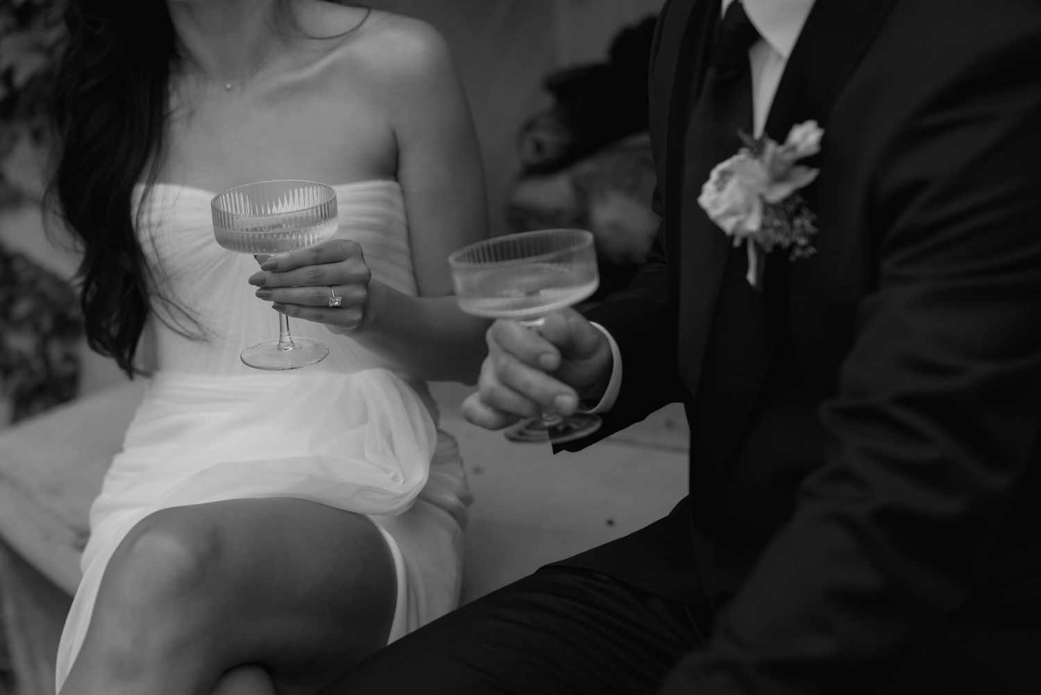 Black and white photo of wedding couple holding champagne glasses during a celebration.