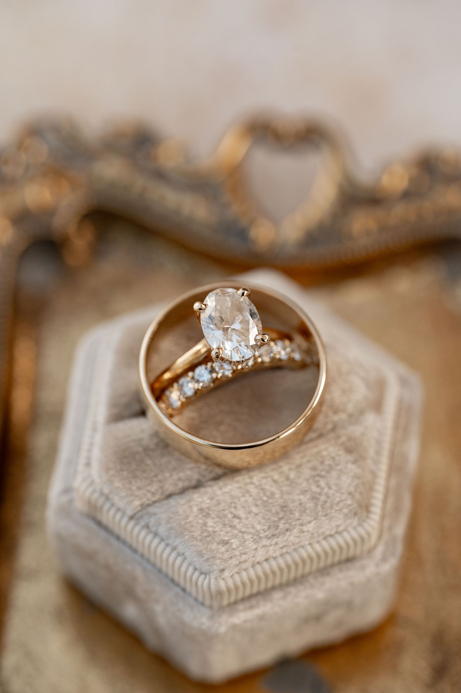 Diamond engagement ring and wedding band arranged on vintage gray velvet ring box.