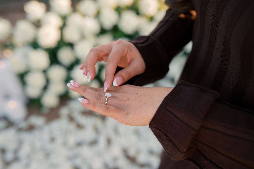 Hands of a bride and groom exchanging wedding rings during a romantic ceremony with bokeh lights in background.