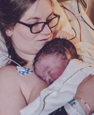 A peaceful moment of bonding with a sleeping newborn in a hospital setting.