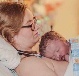 An intimate bonding moment between parent and newborn in soft natural lighting.