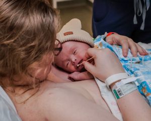 A quiet moment of bonding between parent and newborn on patterned bedding.