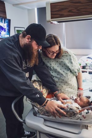 Two people working together at a hospital bassinet or changing station.