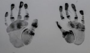 Black handprints and footprints preserved as keepsakes on white paper.