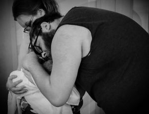 An intimate black and white photograph capturing a tender moment between parent and child.