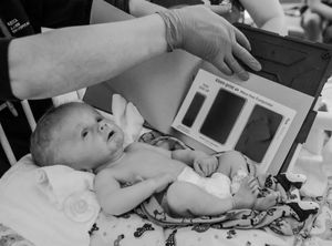 Vintage black and white photo of infant being examined on medical table.