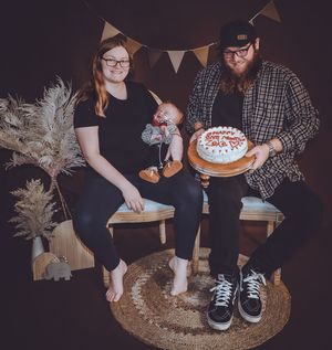 Family photo session on woven mat featuring rustic decor and white triangle banners.