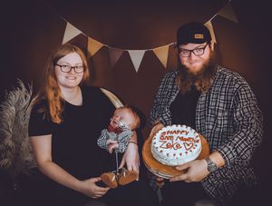 A family photo with bunting decorations and a celebration cake against a dark background.