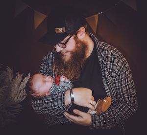 A tender family portrait with plaid shirt and bunting decorations in dramatic lighting.