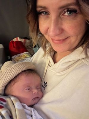 Intimate selfie moment with sleeping newborn wearing knit hat.