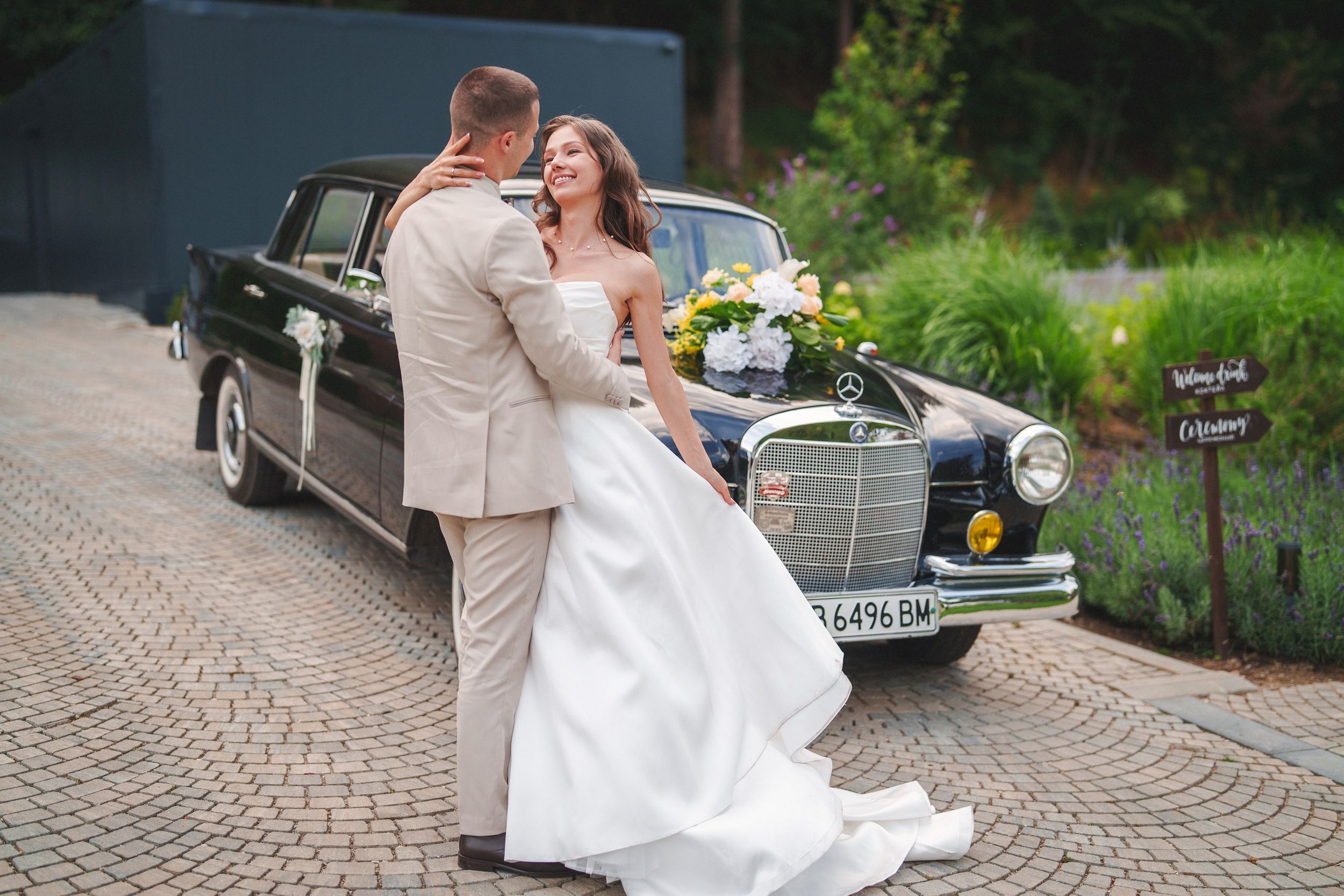 A happy couple shares romantic moments in front of a vintage car during their wedding photoshoot.