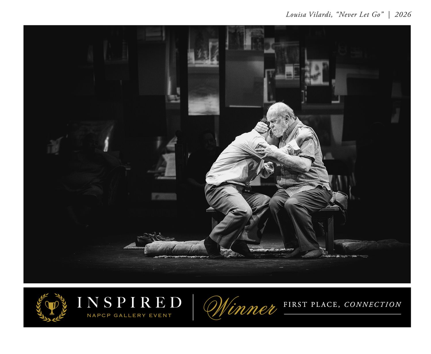 A dramatic black and white photo shows figures lying on a stage floor during a theatrical performance.