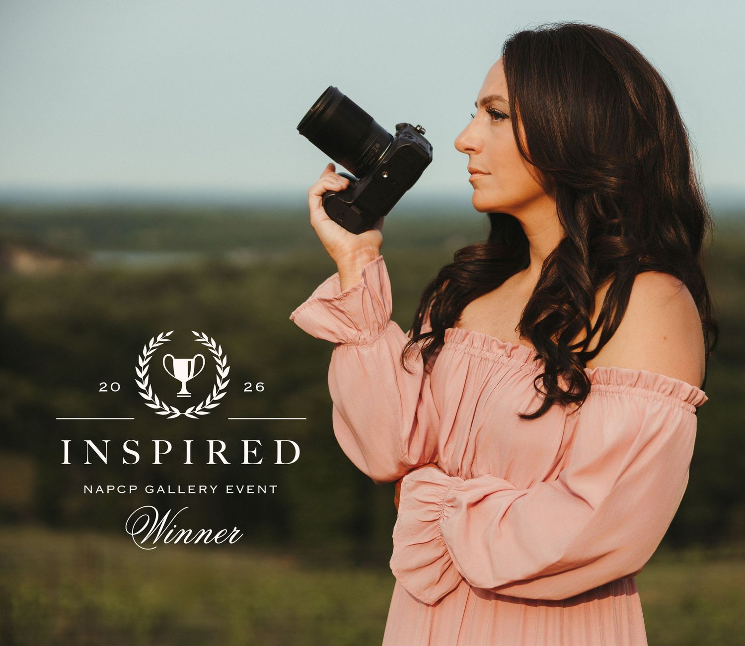 Woman in pink sweater stands in outdoor field during golden hour photography session.