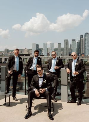 A panoramic view of well-dressed people seated in a row on a rooftop terrace with a city skyline backdrop.