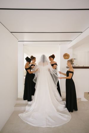 A sequence of photos showing bridesmaids in black dresses helping adjust a flowing white wedding gown train.