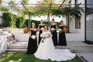 Wedding ceremony setup with white chairs and floral arrangements under a pergola.