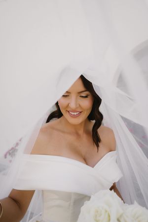 Close-up bridal portrait showing delicate white wedding gown and flowing veil details.