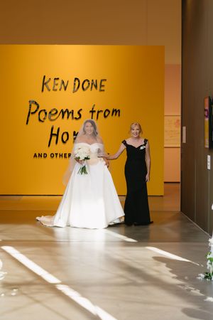 Wedding party posing in front of bright yellow gallery walls with text displays.