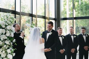 Elegant wedding ceremony with white floral arrangements and formal attire.