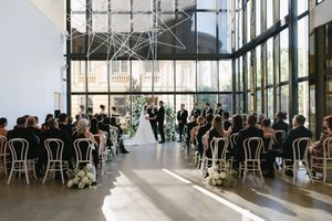 Modern wedding venue with floor-to-ceiling windows and rows of chairs set up for a ceremony.