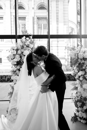 Romantic black and white wedding photos showing newlyweds sharing tender moments between floral arrangements.