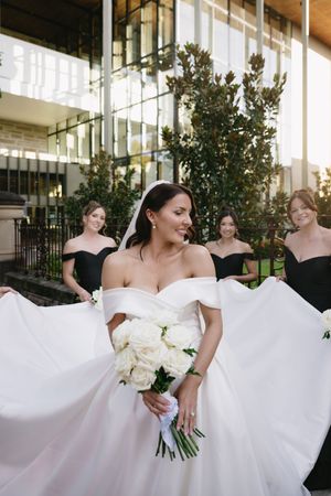 Wedding party in black and white attire posing with the bride's flowing dress.