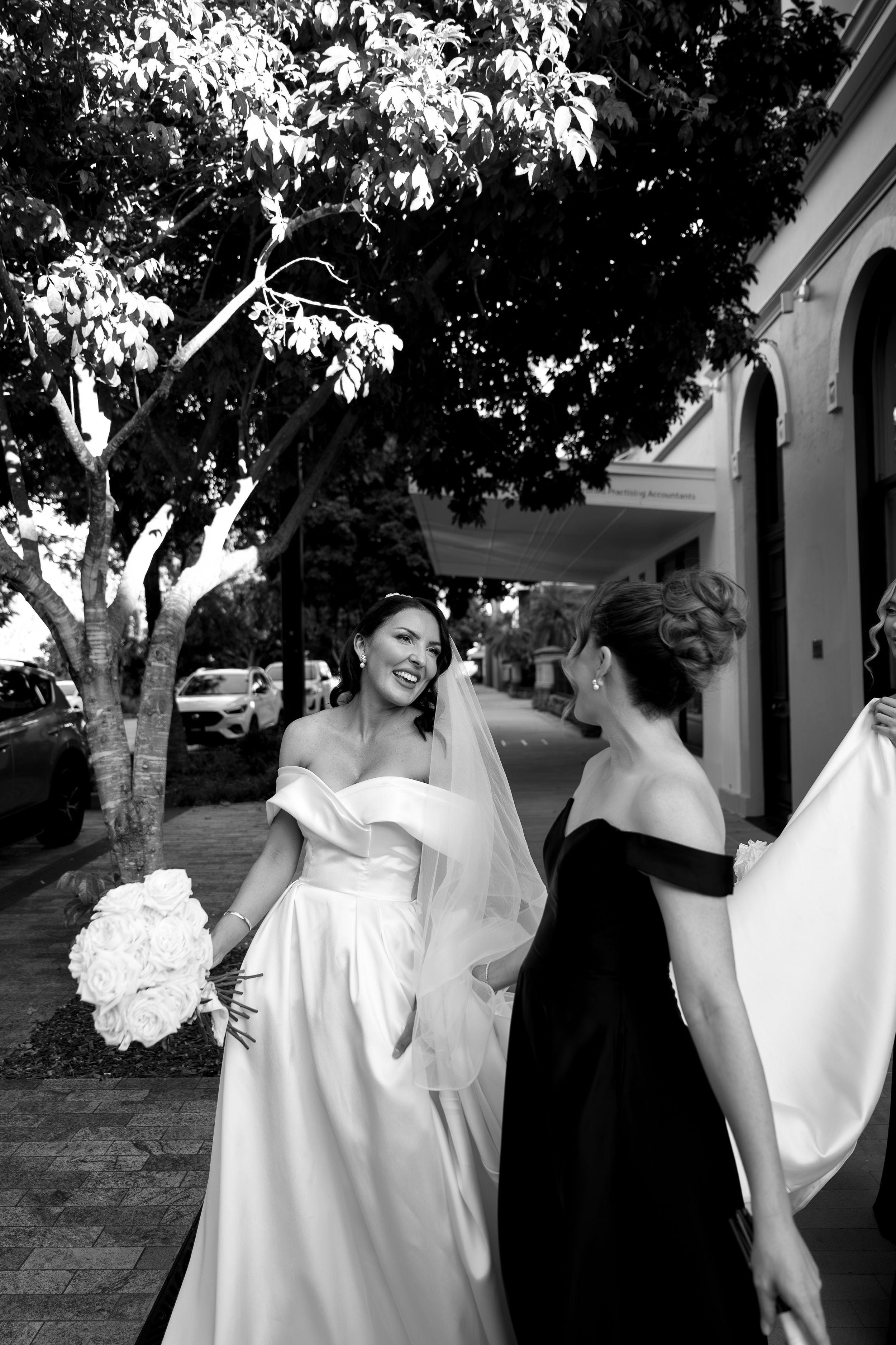 A black and white photo series showing a joyful wedding moment with a bride in white dress and groom in dark suit outdoors.