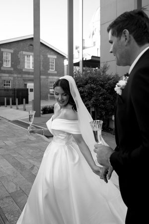 A black and white photo of a couple holding champagne glasses during their wedding celebration.