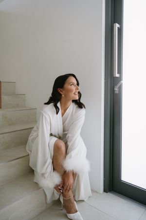 Artistic portrait series showing someone in flowing white clothing sitting by a window with minimalist interior design.