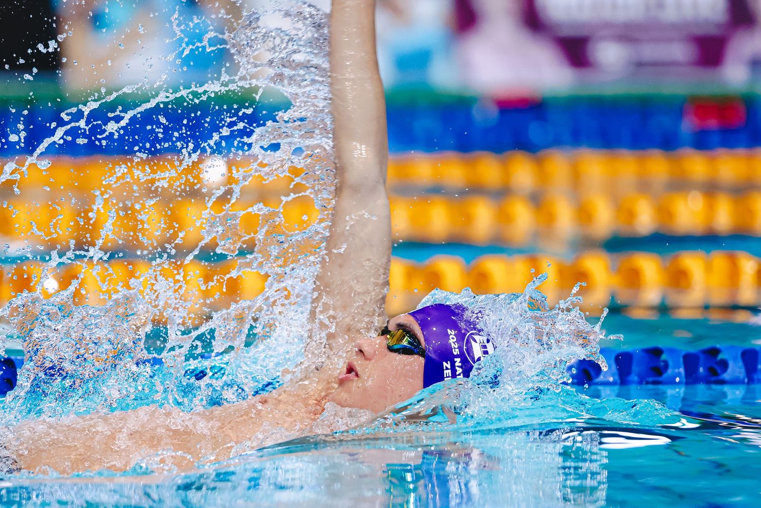 Competitive swimmers racing butterfly stroke in a pool with splashing water and lane dividers.