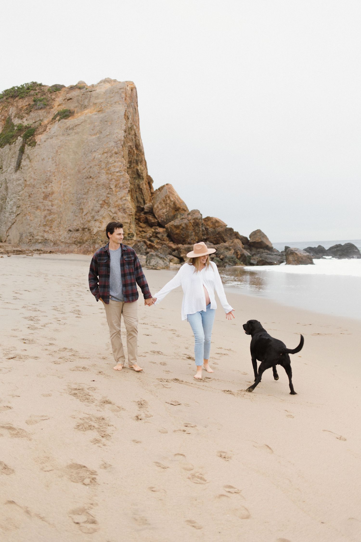 Beach maternity session at Point Dume in Malibu with a couple walking along the shore with their dog