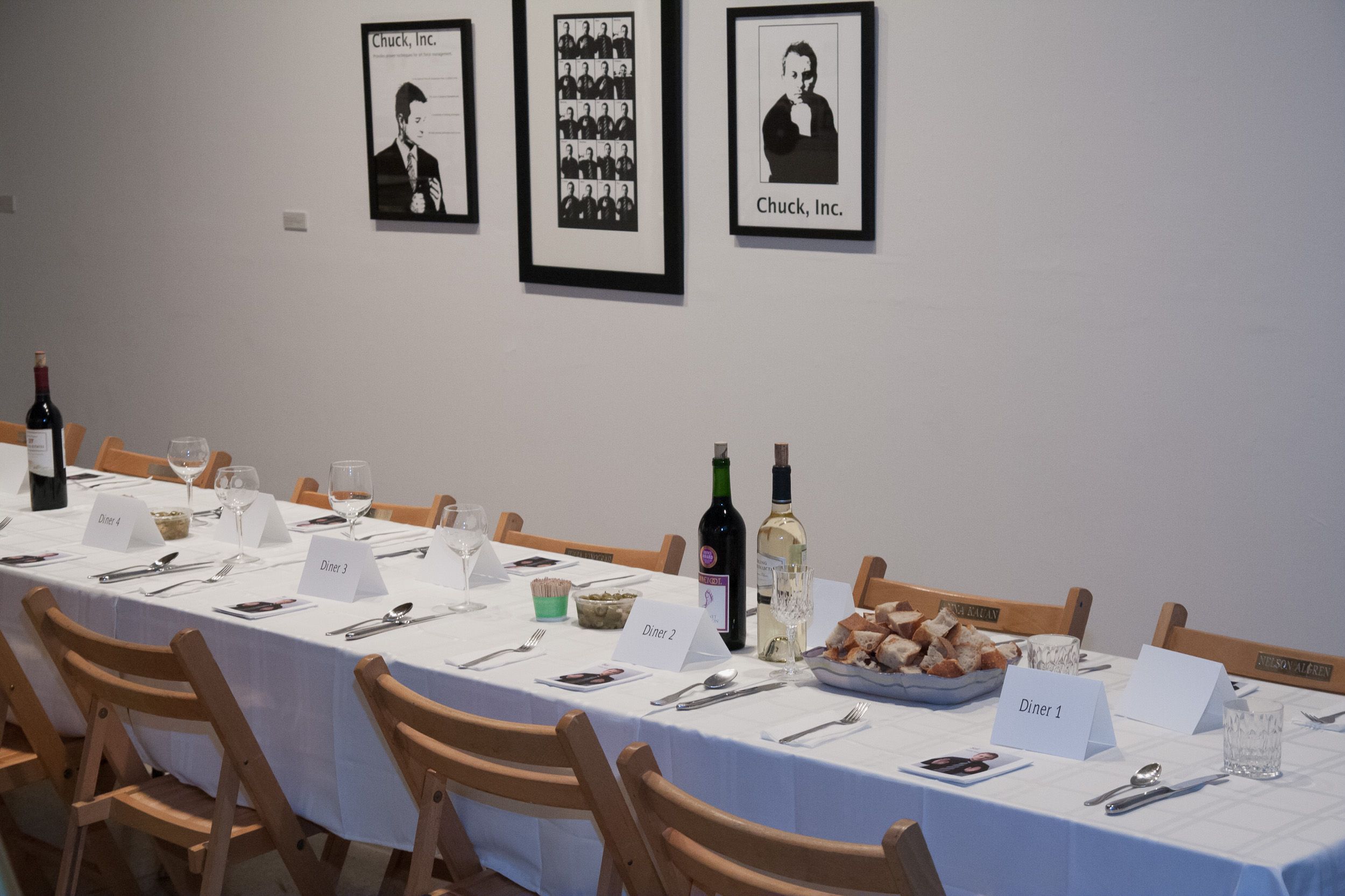 Gallery dining room setup with framed photographs on white walls and table settings.