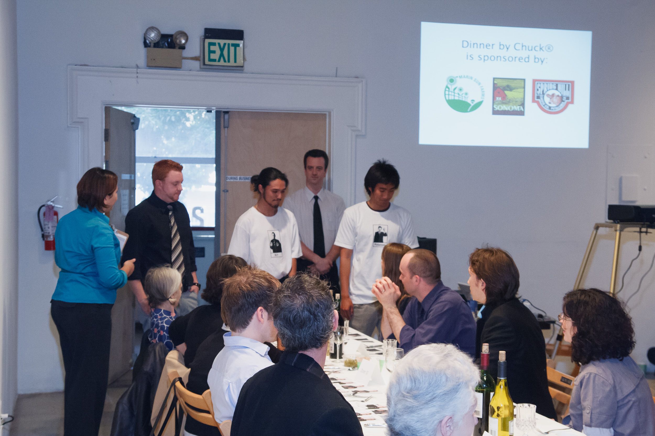 Conference room setup with projector screen and attendees gathered at tables for a professional event.
