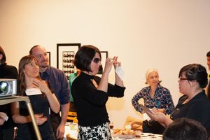 People seated at tables in a gallery space having an interactive discussion during an event.