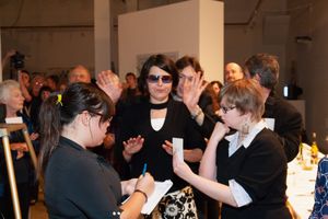 Crowd of attendees participating in an interactive gallery event with raised hands.