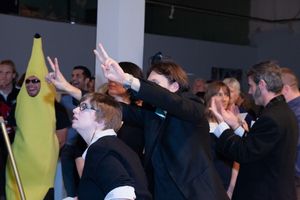 People in formal attire gesturing and participating in a group activity.