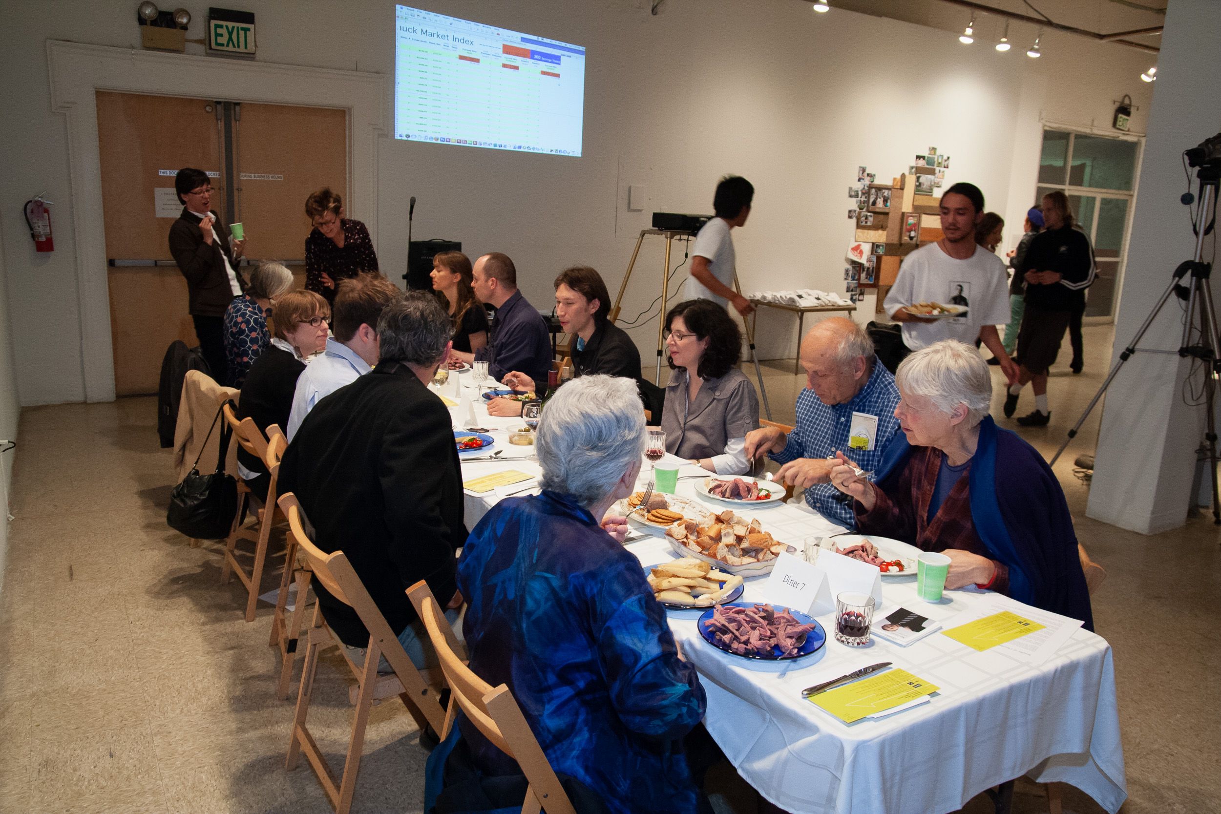 People seated at tables in an art gallery space during a presentation or workshop.
