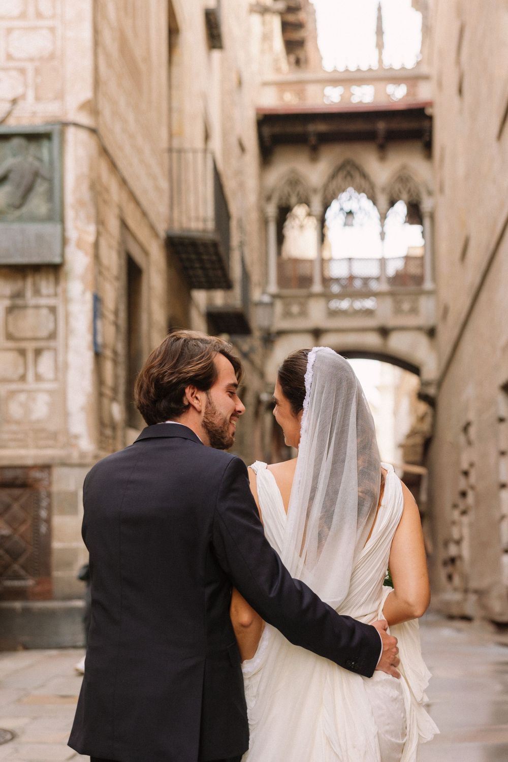 Couple embracing in Gothic quarter with historic architecture backdrop.