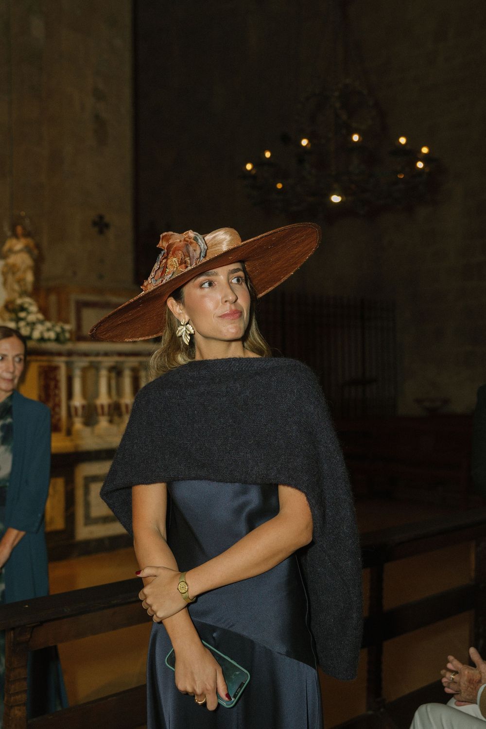 Wedding guests dancing in formal attire with one wearing a distinctive wide-brimmed brown hat.