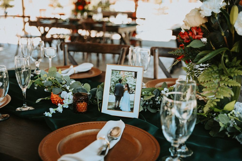 Elegant table setting with crystal wine glasses, terra cotta plates and fresh greenery at an indoor reception.